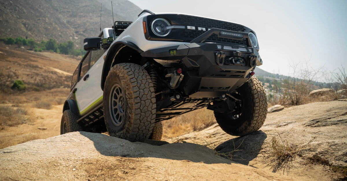 Picture of a Ford Bronco with front wheels on a rock with skid plate clearly visible and front steel bumper with bull bar