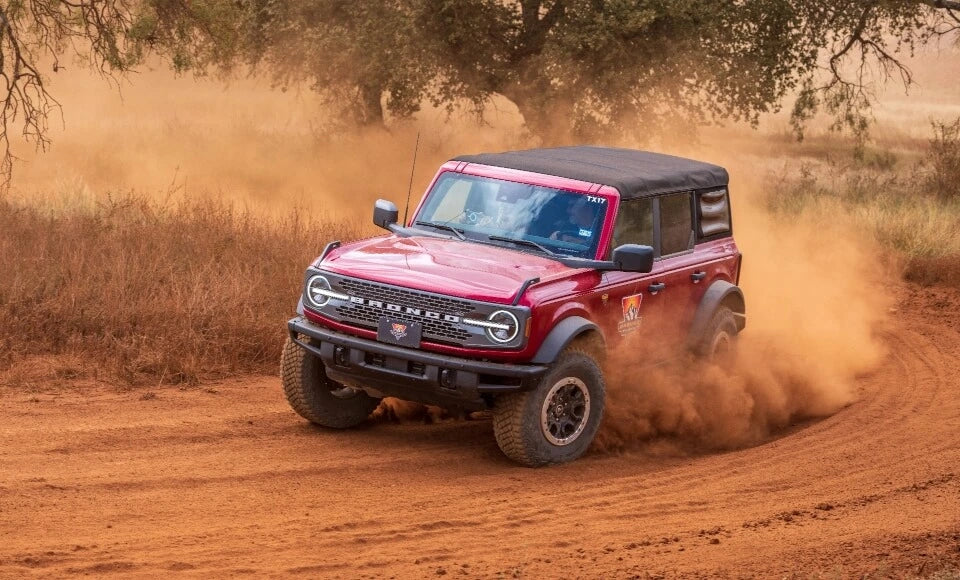 Red Ford Bronco in the desert with a sand cloud