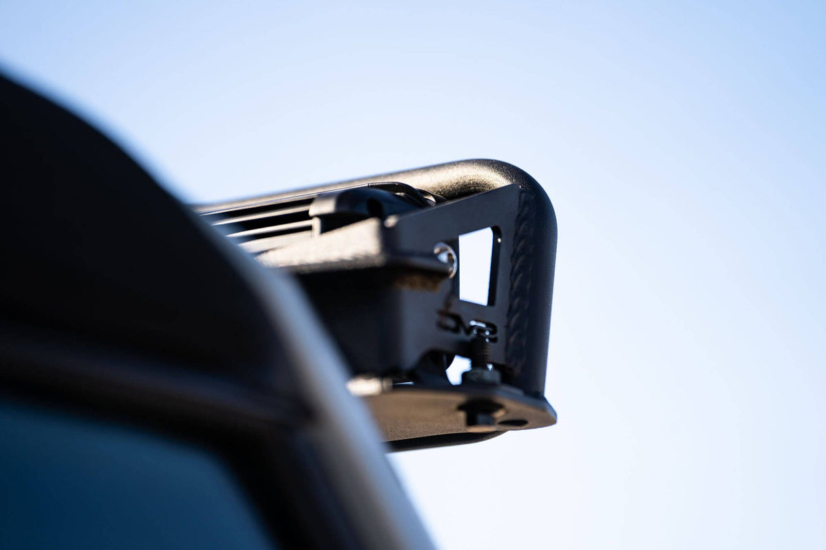 DV8 Offroad 52-inch straight light bar mount installed on 2021-2026 Ford Bronco close-up showing bracket at windshield frame