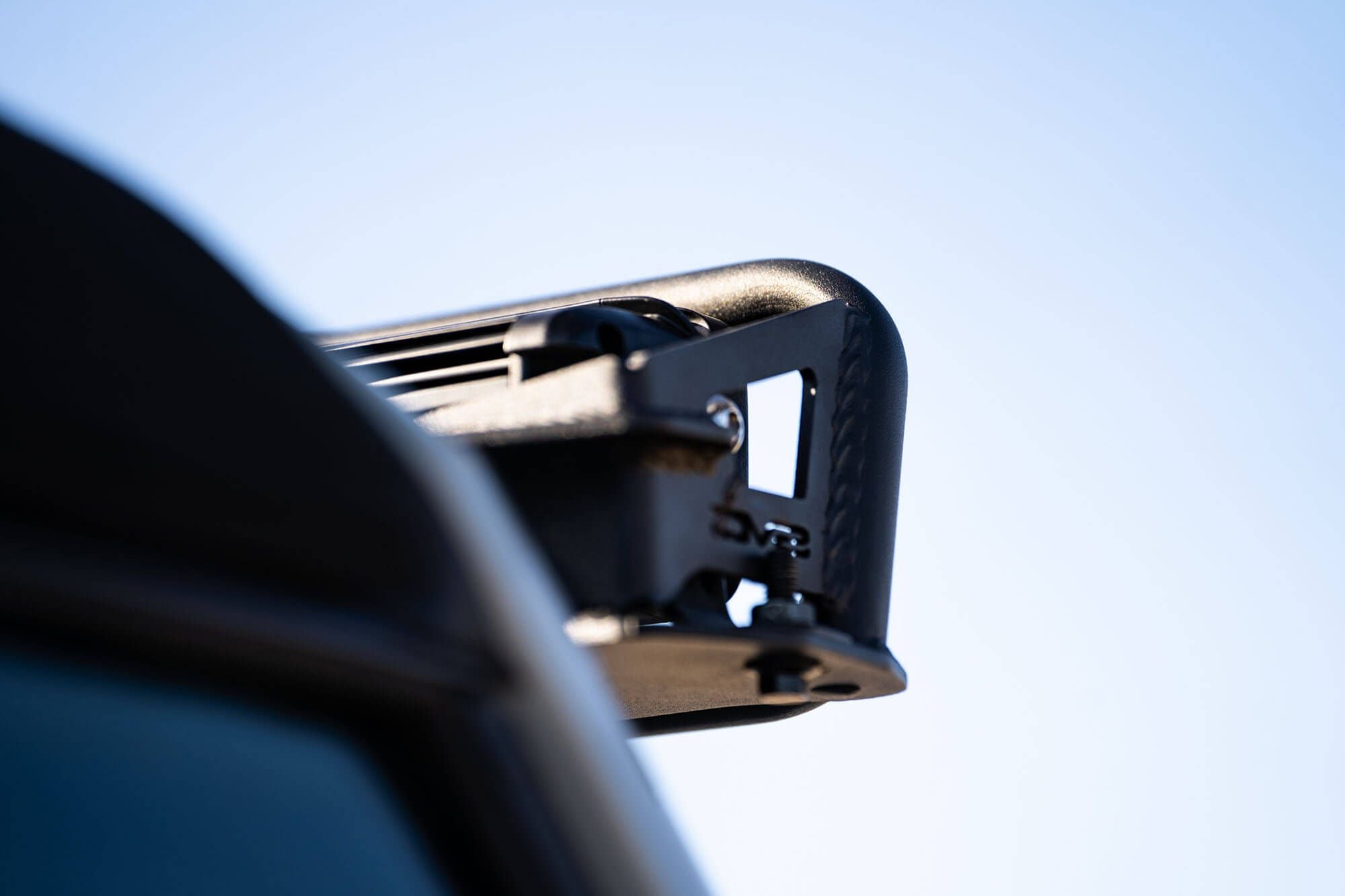 DV8 Offroad 52-inch straight light bar mount installed on 2021-2026 Ford Bronco close-up showing bracket at windshield frame