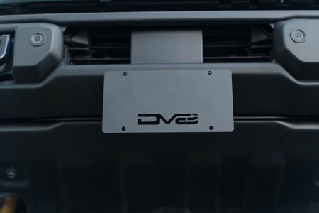 DV8 Offroad license plate mount installed on 2021-2026 Ford Bronco front view showing license plate position on Capable bumper