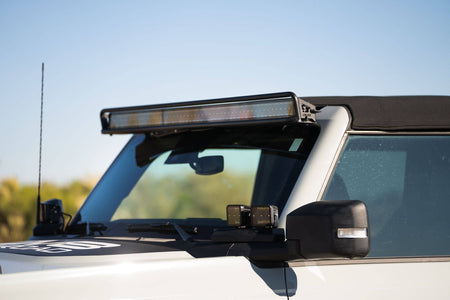 DV8 Offroad 52-inch straight light bar mount installed on 2021-2026 Ford Bronco showing amber LED light bar lit above windshield