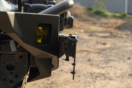 DV8 Offroad universal D-ring license plate mount installed on off-road vehicle side angle view outdoor setting