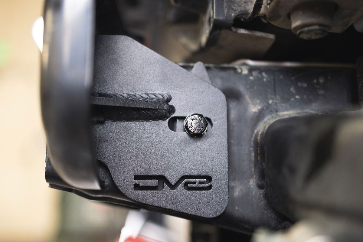 DV8 Offroad frame horn reinforcement bracket installed on Ford Bronco frame, close-up showing DV8 logo plate