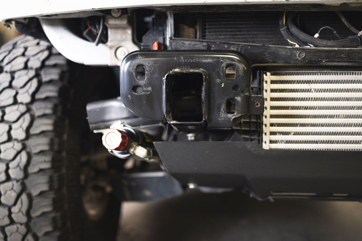 DV8 Offroad frame horn reinforcement bracket installed on Ford Bronco, undercarriage view showing intercooler and frame
