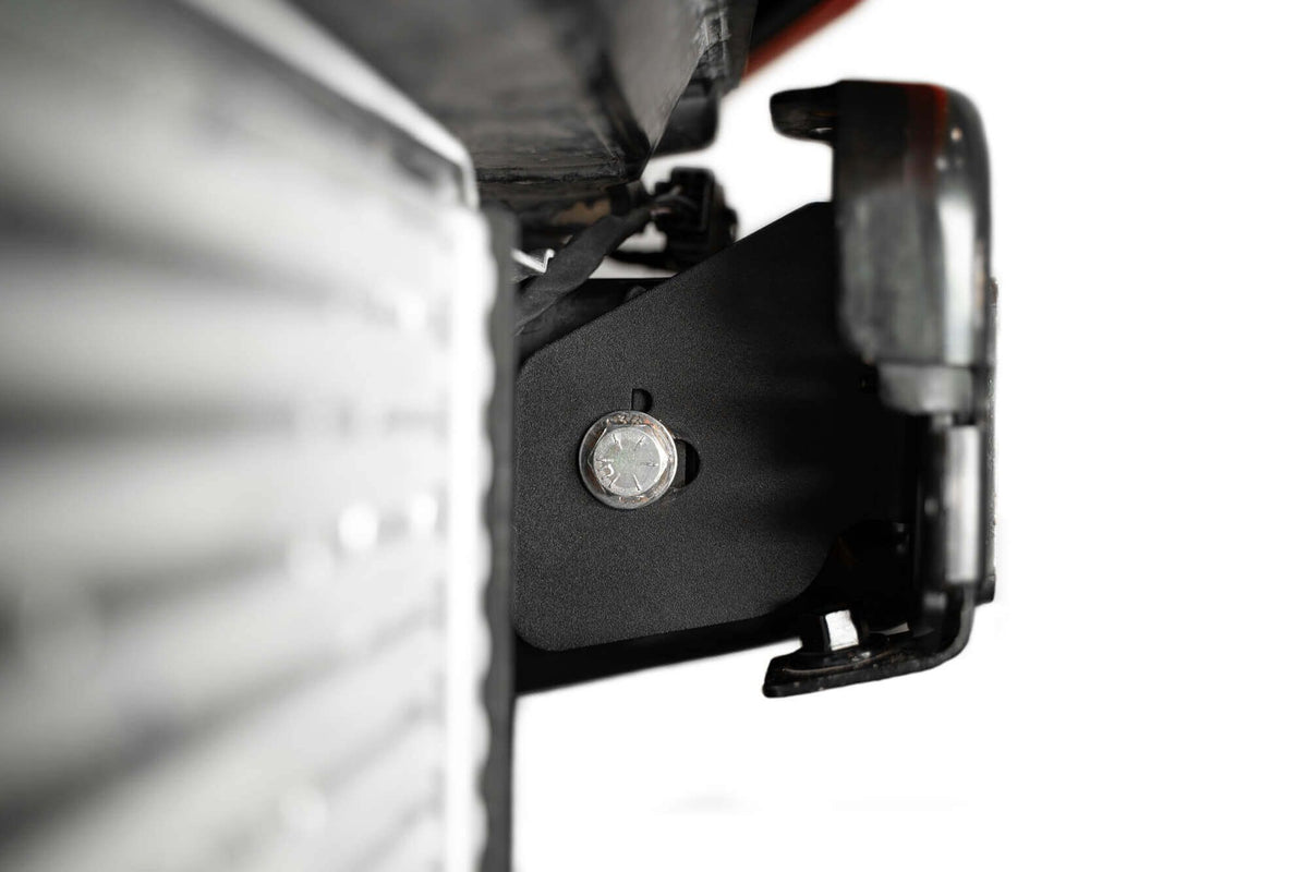 Addictive Desert Designs frame horn gusset installed on Ford Bronco frame, close-up near headlight reflector housing