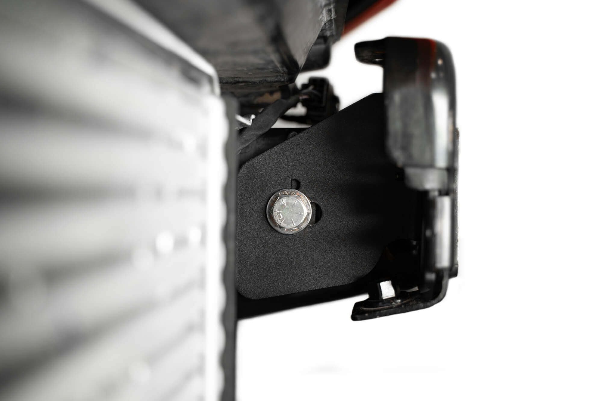 Addictive Desert Designs frame horn gusset installed on Ford Bronco frame, close-up near headlight reflector housing