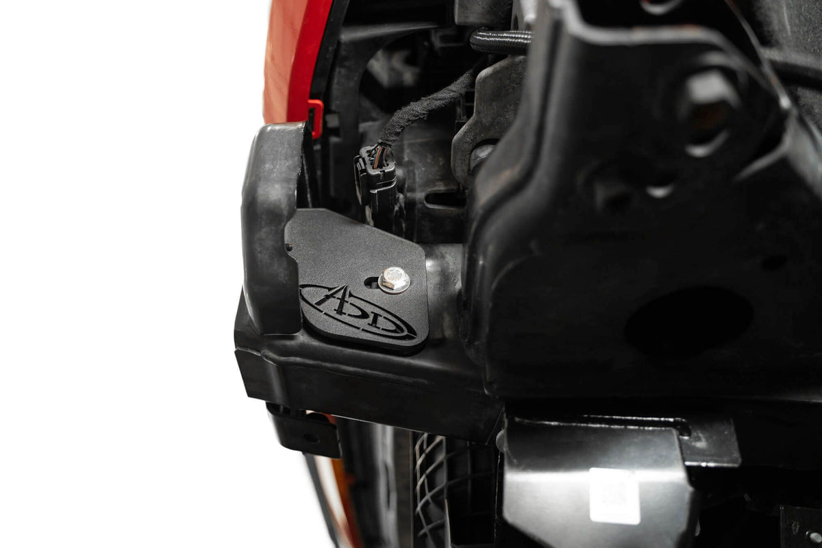 Addictive Desert Designs frame horn gusset installed on Ford Bronco frame, close-up near headlight wiring and components