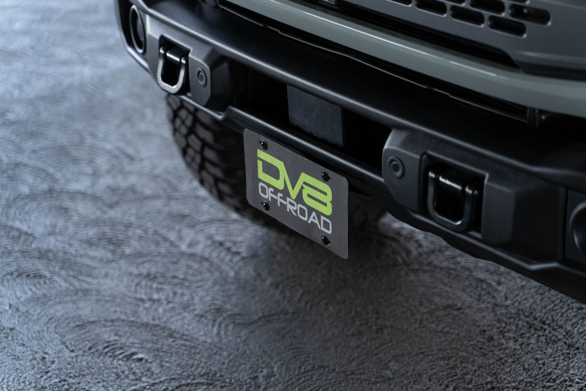 DV8 Offroad license plate mount installed on 2021-2026 Ford Bronco angle view showing bracket mounted on Capable bumper