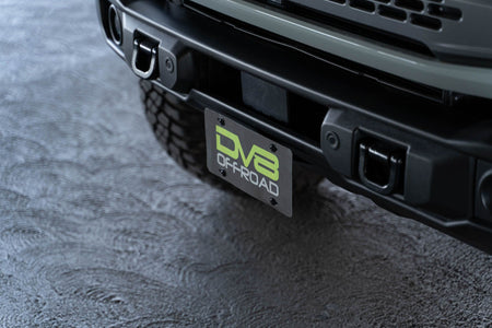 DV8 Offroad license plate mount installed on 2021-2026 Ford Bronco angle view showing bracket mounted on Capable bumper