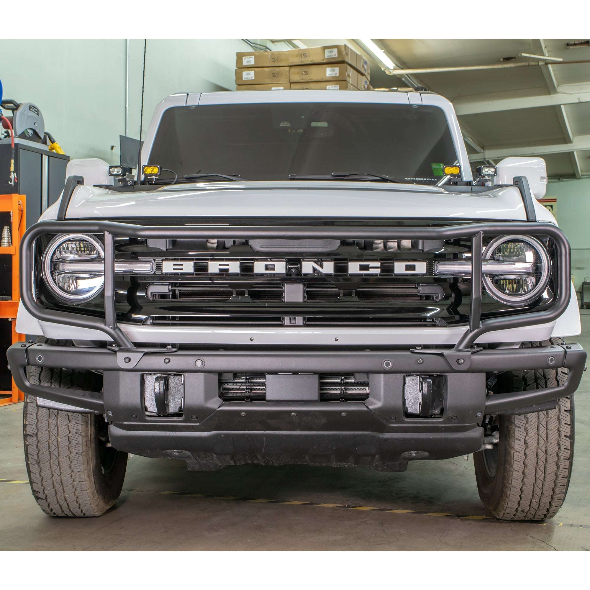 Turn Offroad modular bumper grille guard installed on white Ford Bronco, front three-quarter view in warehouse setting