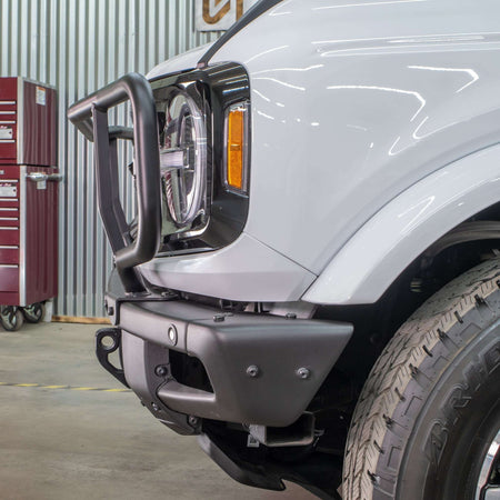 Turn Offroad modular bumper grille guard installed on white Ford Bronco, side close-up showing fender and wheel in shop setting