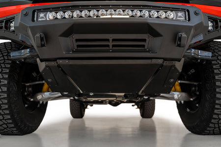 Addictive Desert Designs Stealth Fighter front bumper installed on Ford Bronco, underside close-up showing skid plate, product shot on white background