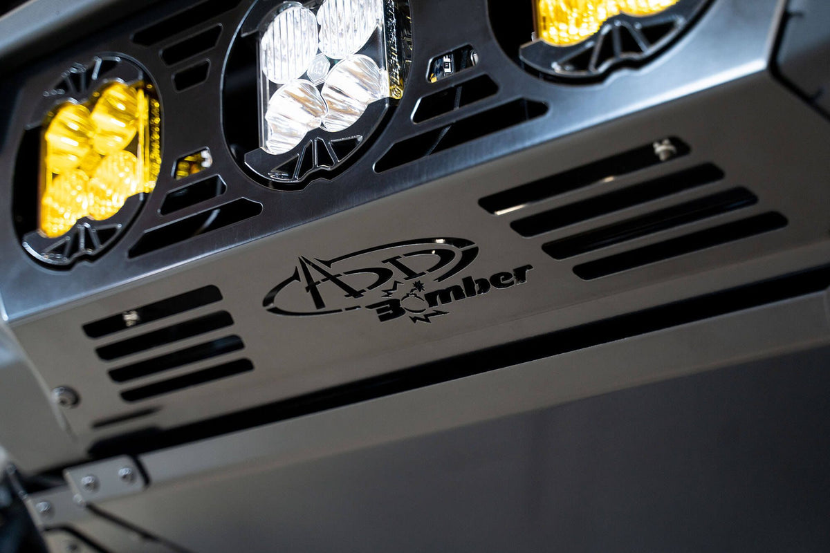 Addictive Desert Designs Bomber Baja front bumper close-up showing amber and white light pod cluster with ADD Bomber badge