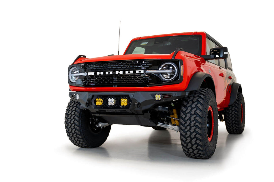 Addictive Desert Designs Bomber Baja front bumper installed on orange Ford Bronco, front three-quarter view product shot on white background