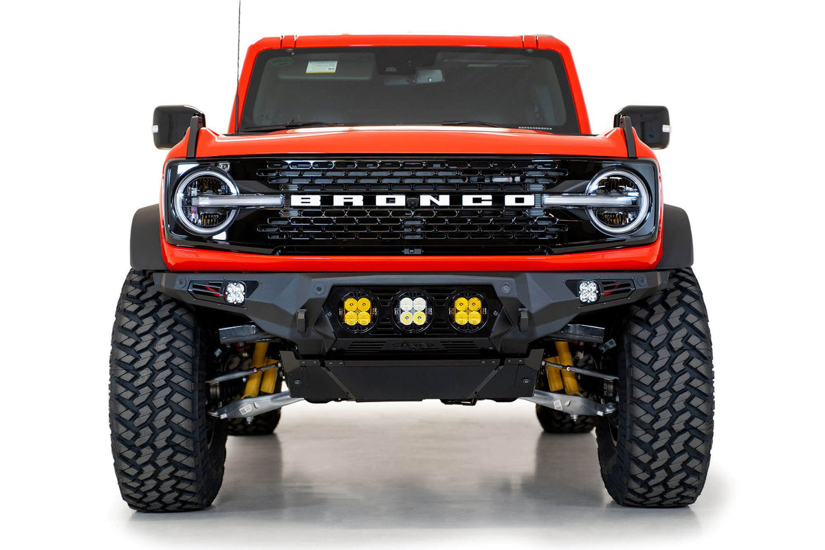 Addictive Desert Designs Bomber Baja front bumper installed on orange Ford Bronco, straight-on front view product shot on white background