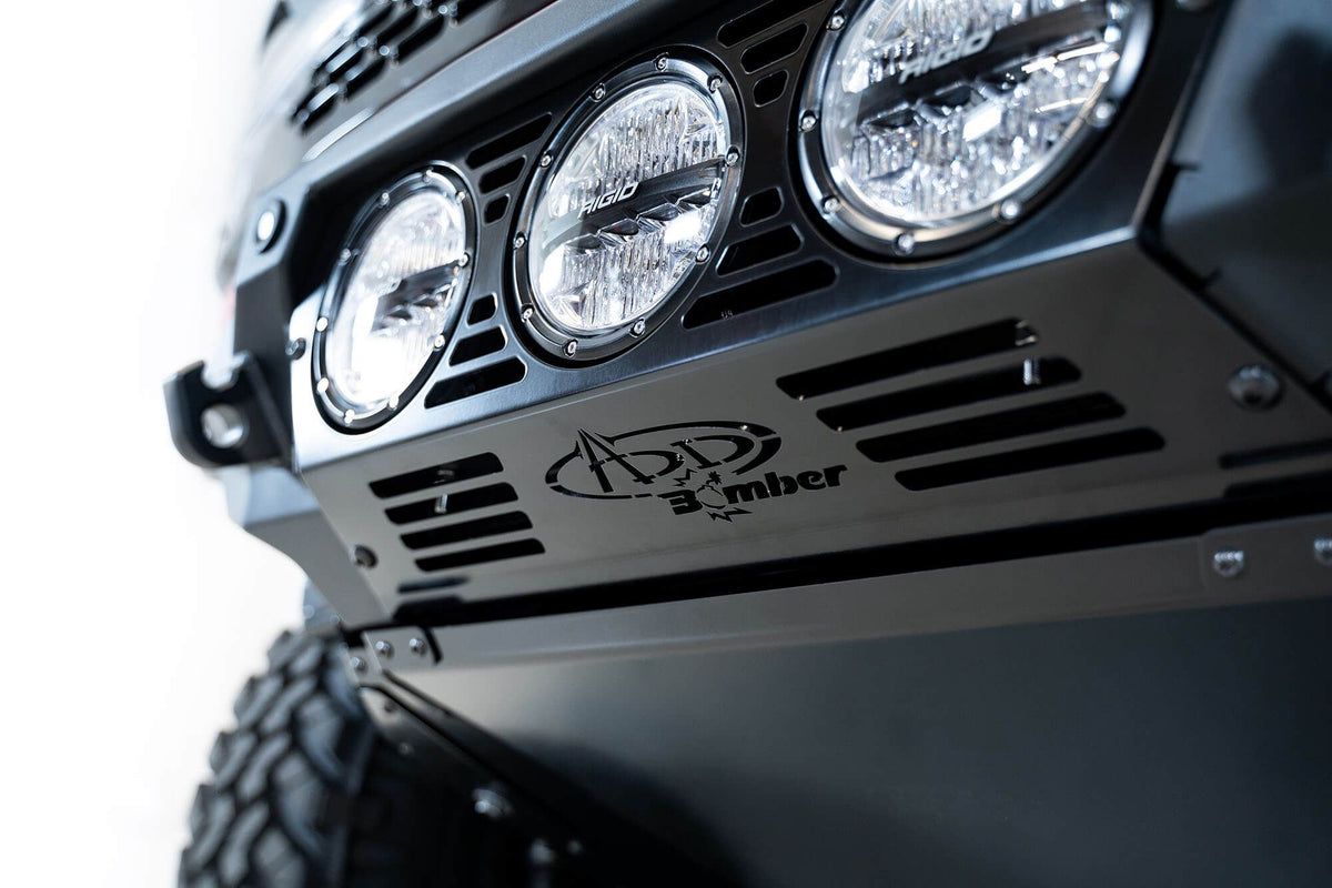 Addictive Desert Designs Bomber Rigid front bumper close-up showing three-light pod cluster with ADD Bomber badge