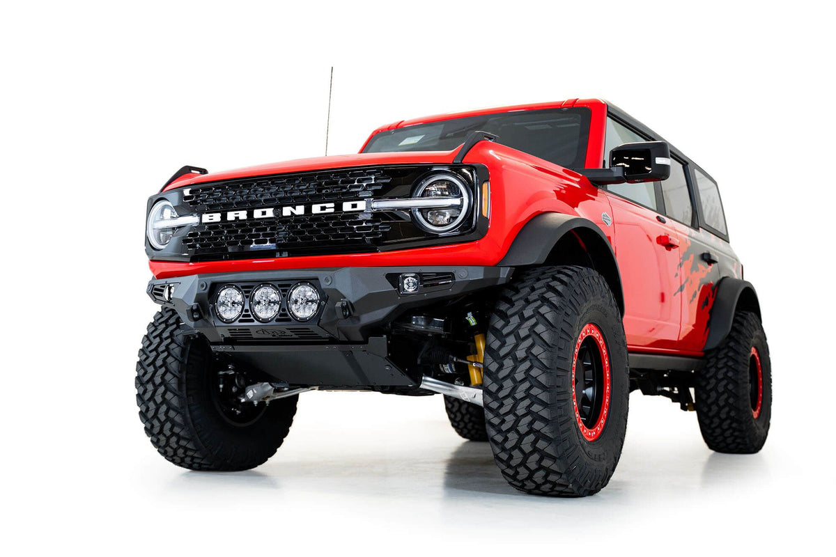 Addictive Desert Designs Bomber Rigid front bumper installed on red Ford Bronco, front three-quarter view product shot on white background
