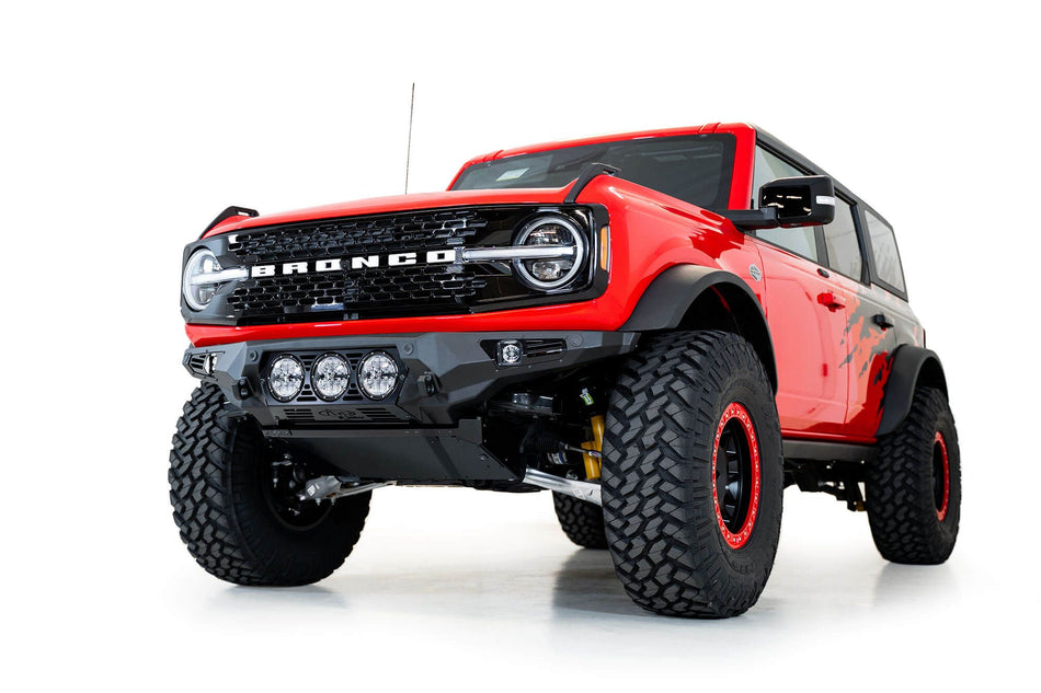 Addictive Desert Designs Bomber Rigid front bumper installed on red Ford Bronco, front three-quarter view product shot on white background