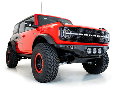 Addictive Desert Designs Bomber Rigid front bumper installed on red Ford Bronco, front three-quarter view showing full vehicle, product shot on white background
