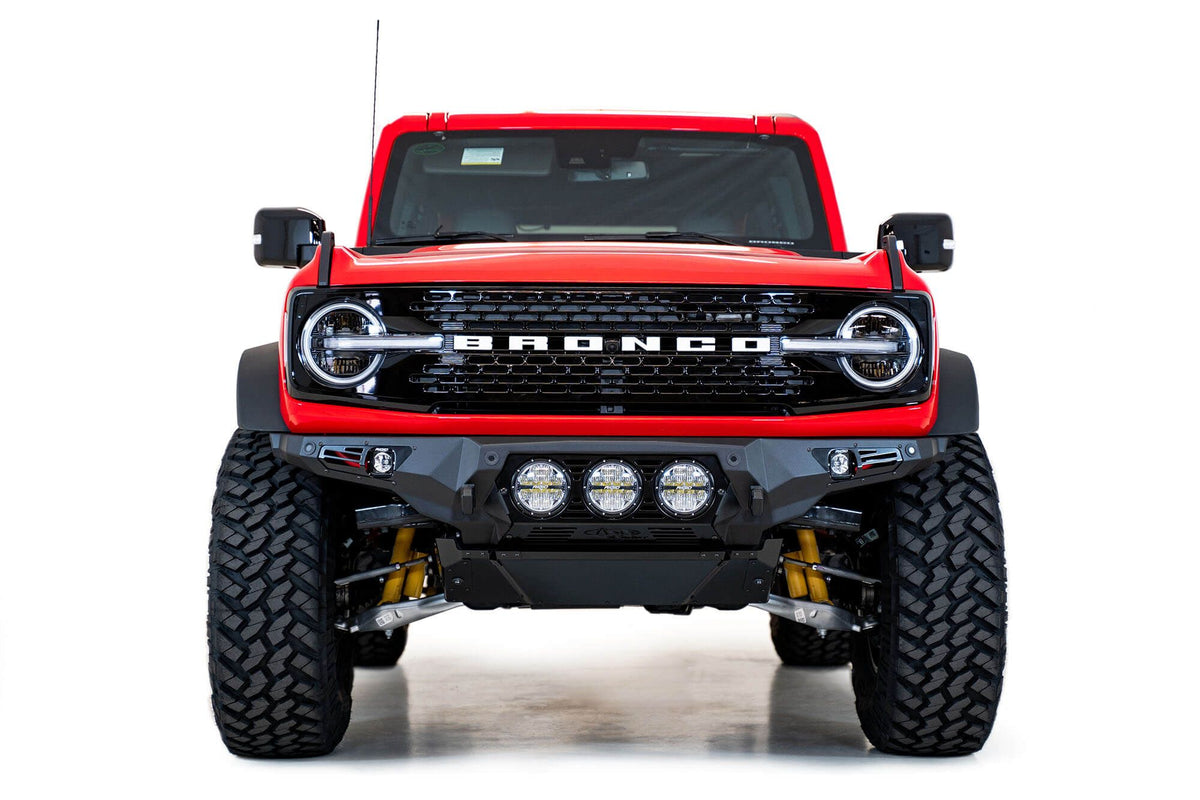 Addictive Desert Designs Bomber Rigid front bumper installed on red Ford Bronco, straight-on front view product shot on white background