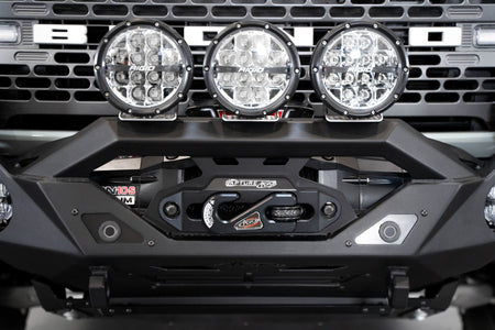 Addictive Desert Designs Krawler front bumper installed on gray Ford Bronco with amber marker lights, straight-on close-up showing full light row across bumper