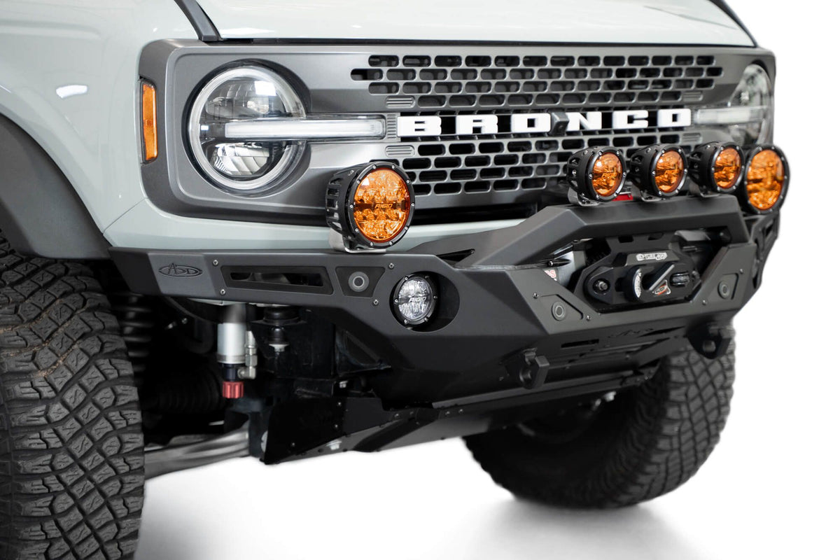 Addictive Desert Designs Krawler front bumper installed on gray Ford Bronco with amber marker lights, front three-quarter close-up view, second angle