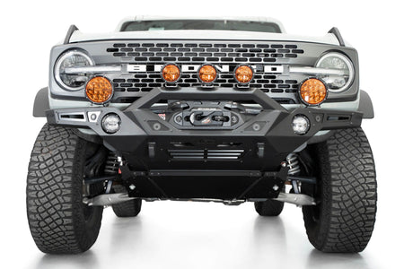Addictive Desert Designs Krawler front bumper installed on gray Ford Bronco with amber marker lights, front three-quarter close-up view, third angle