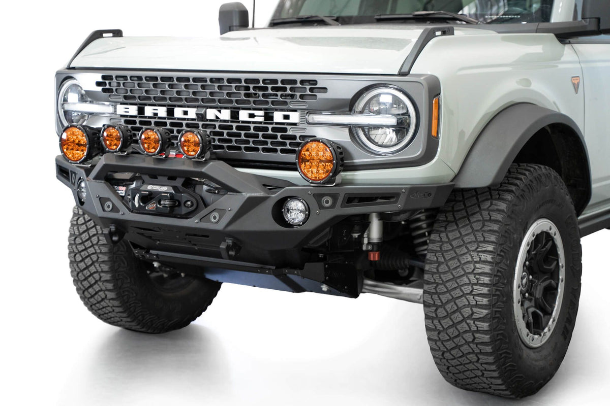 Addictive Desert Designs Krawler front bumper installed on gray Ford Bronco with amber marker lights, front three-quarter close-up view, alternate angle
