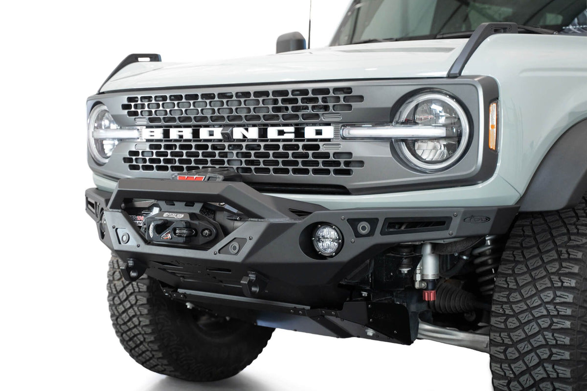 Addictive Desert Designs Krawler front bumper installed on gray Ford Bronco with amber marker lights, front three-quarter close-up view