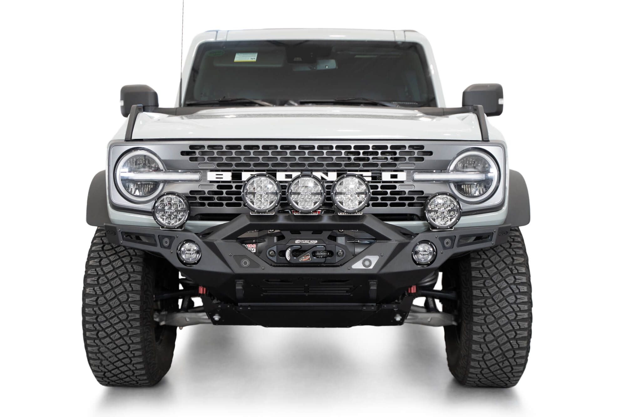 Addictive Desert Designs Krawler front bumper installed on gray Ford Bronco with amber marker lights, straight-on front view of full vehicle, product shot on white background