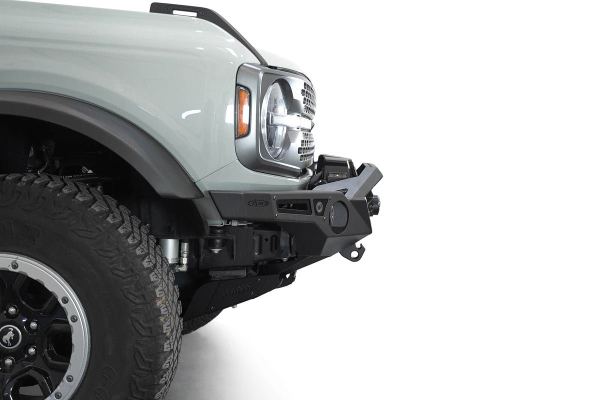 Addictive Desert Designs Krawler front bumper installed on gray Ford Bronco, close-up showing fender, headlight, and bumper corner