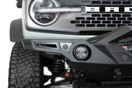 Addictive Desert Designs Krawler front bumper installed on gray Ford Bronco, close-up showing grille and bumper