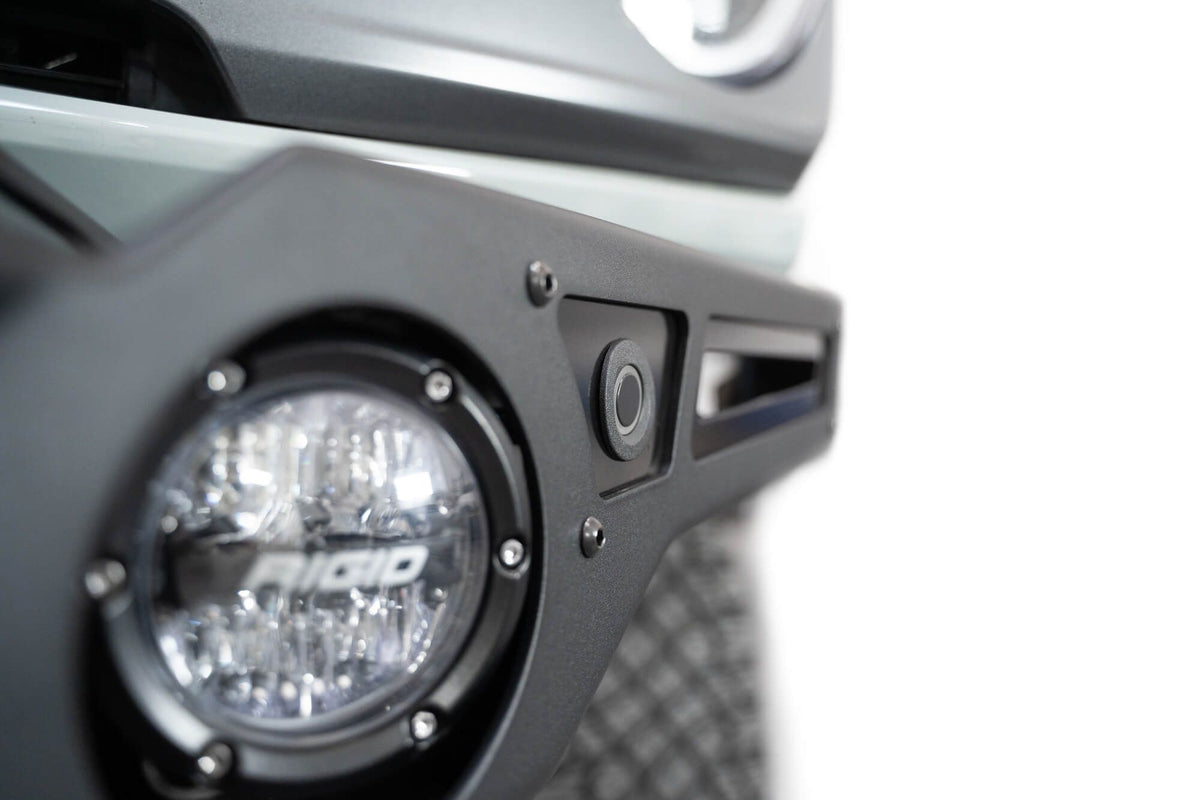 Addictive Desert Designs Krawler front bumper installed on gray Ford Bronco, close-up showing headlight and bumper corner