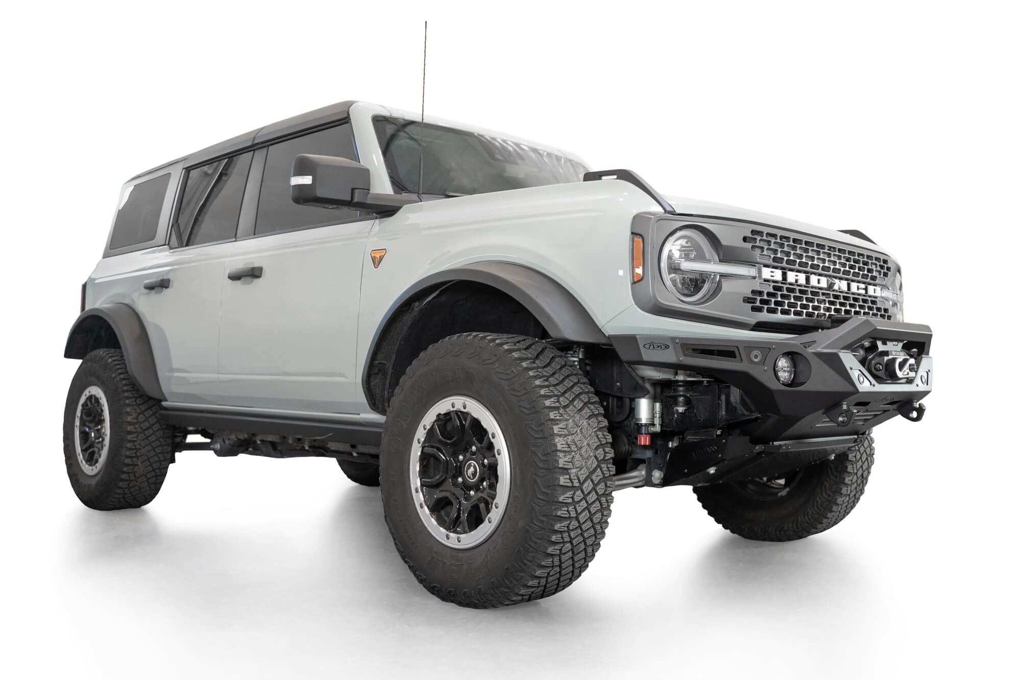 Addictive Desert Designs Krawler front bumper installed on gray Ford Bronco, front three-quarter view of full vehicle, product shot on white background