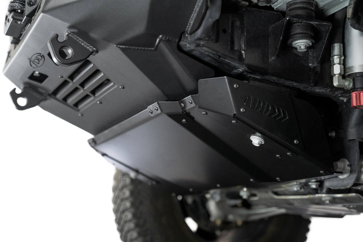 Addictive Desert Designs Krawler front bumper installed on Ford Bronco, underside close-up showing skid plate, angled view