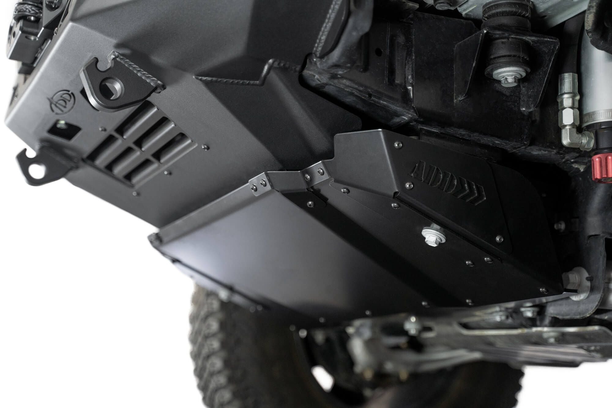 Addictive Desert Designs Krawler front bumper installed on Ford Bronco, underside close-up showing skid plate, angled view
