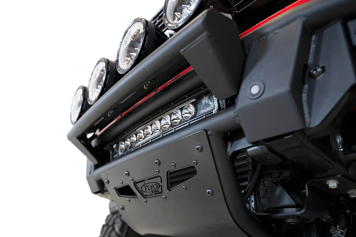 Addictive Desert Designs PRO Bolt-On front bumper installed on red Ford Bronco, angled close-up showing bumper corner and light bar mount