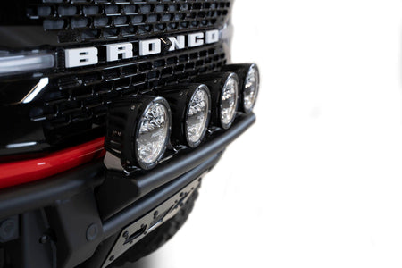 Addictive Desert Designs PRO Bolt-On front bumper installed on red Ford Bronco, straight-on close-up showing light bar and BRONCO grille badge