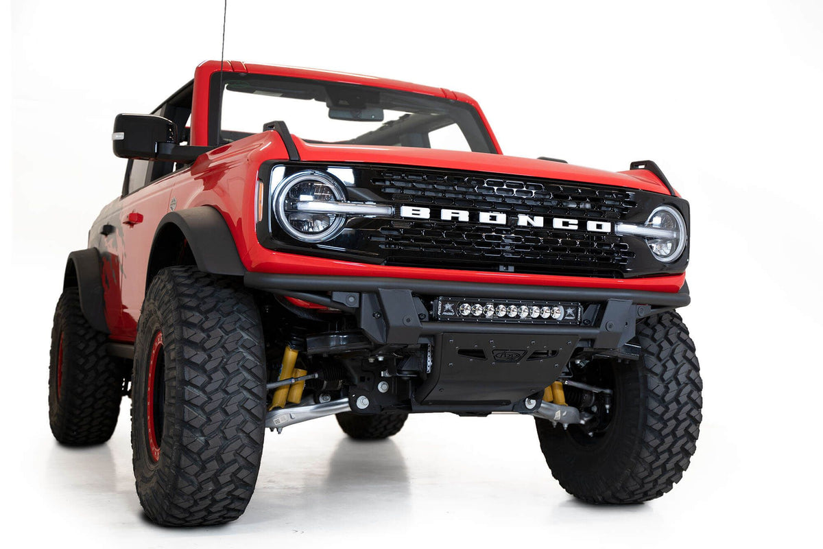 Addictive Desert Designs PRO Bolt-On front bumper installed on red Ford Bronco, front three-quarter view of full vehicle with soft top down, product shot on white background