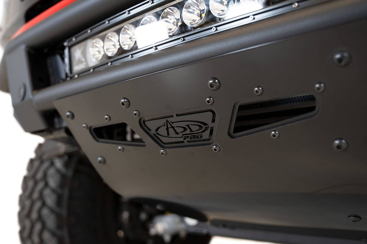 Addictive Desert Designs PRO Bolt-On front bumper installed on Ford Bronco, underside close-up showing skid plate with ADD logo