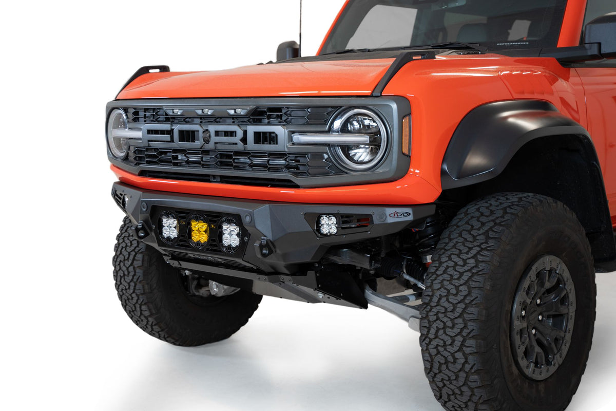 Addictive Desert Designs Bomber Baja front bumper installed on Ford Bronco Raptor, close-up showing headlight and bumper corner detail
