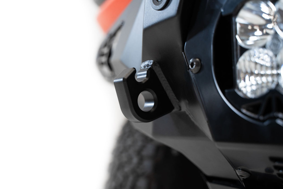Addictive Desert Designs Bomber Baja front bumper installed on Ford Bronco Raptor, close-up showing single white light pod on bumper corner