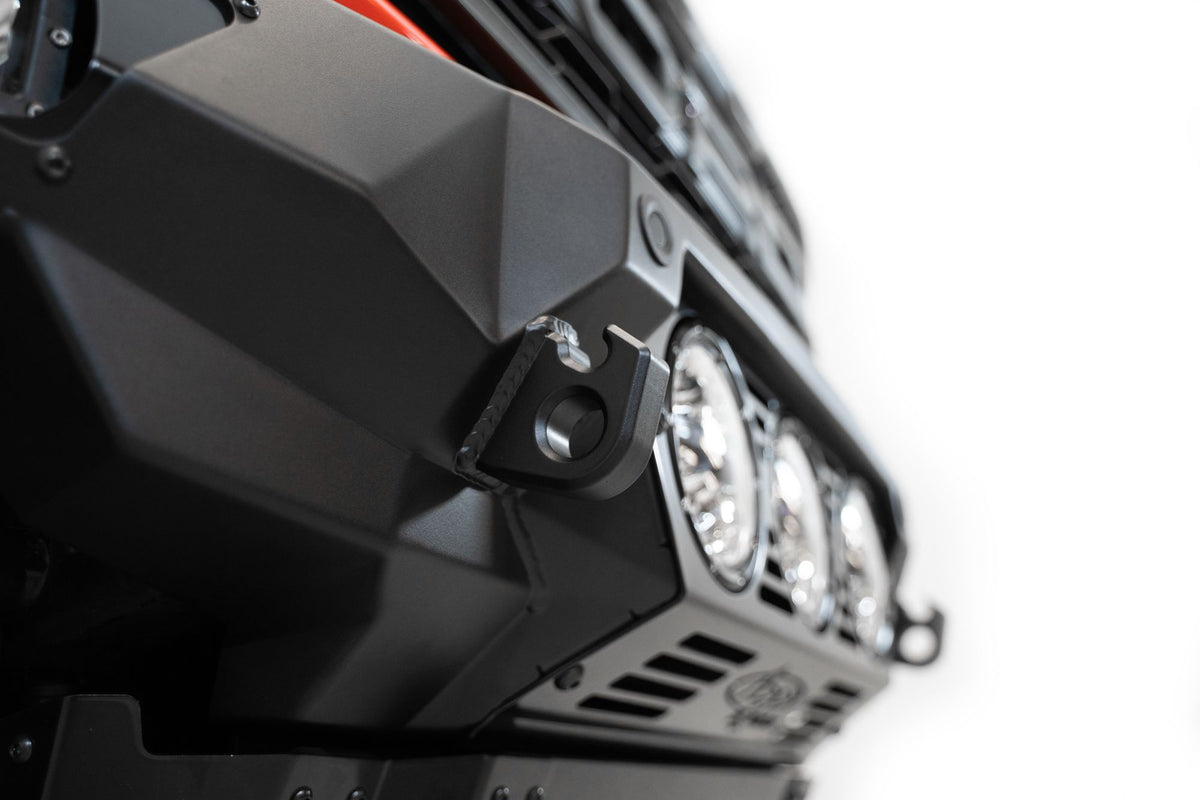 Addictive Desert Designs Bomber front bumper installed on Ford Bronco Raptor, angled close-up showing bumper corner and light pod