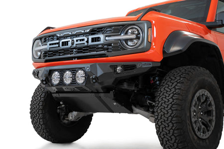 Addictive Desert Designs Bomber front bumper installed on orange Ford Bronco Raptor, angled front three-quarter close-up product shot on white background