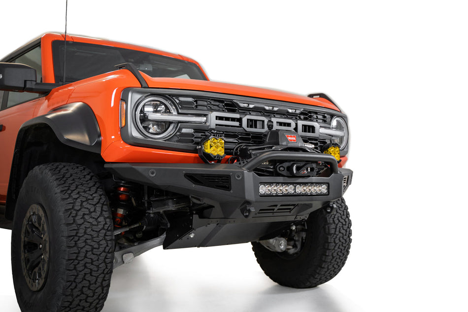 Addictive Desert Designs Rock Fighter front bumper installed on orange Ford Bronco Raptor, front three-quarter close-up product shot on white background