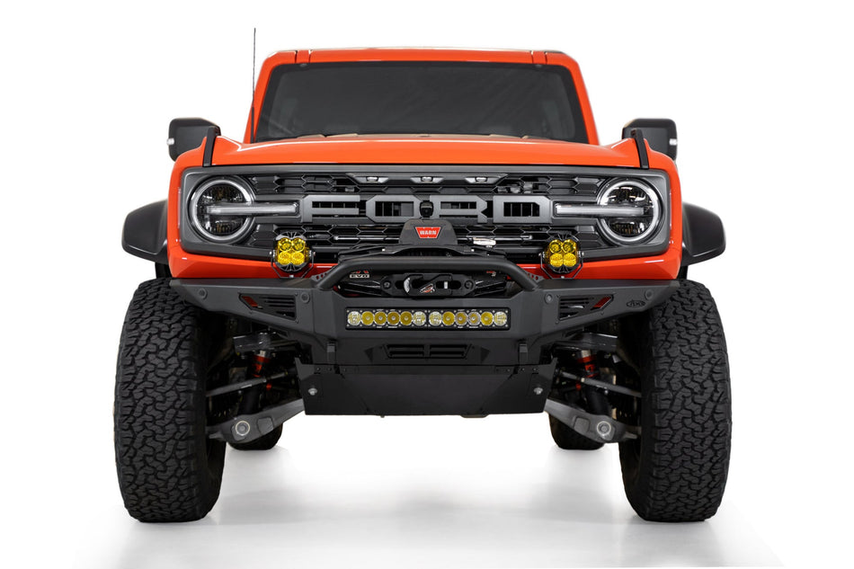 Addictive Desert Designs Rock Fighter front bumper installed on orange Ford Bronco Raptor, straight-on front view product shot on white background