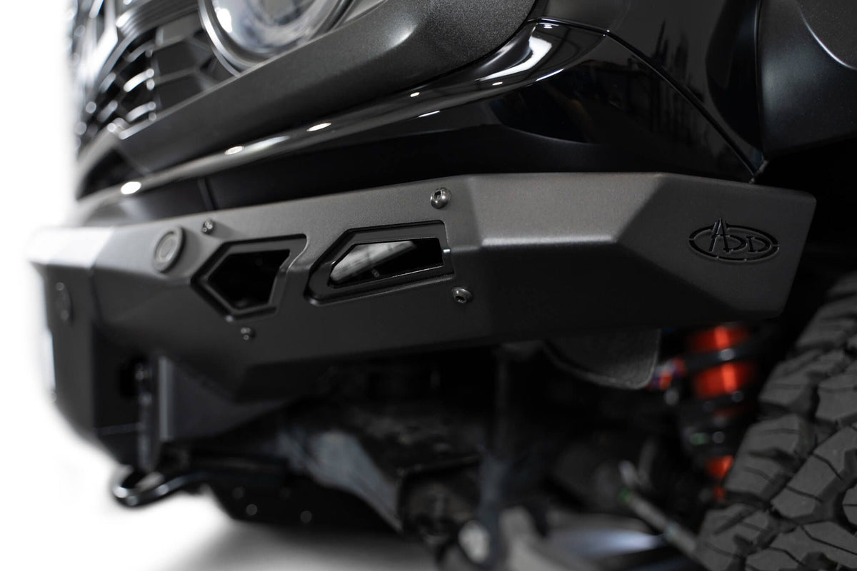 Addictive Desert Designs Phantom front bumper installed on black Ford Bronco Raptor, angled close-up showing bumper corner