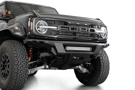 Addictive Desert Designs Phantom front bumper installed on black Ford Bronco Raptor, close-up front three-quarter view showing integrated light bar