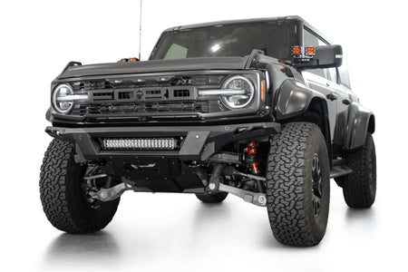 Addictive Desert Designs Phantom front bumper installed on black Ford Bronco Raptor, front three-quarter view with roof rack and marker lights, product shot on white background